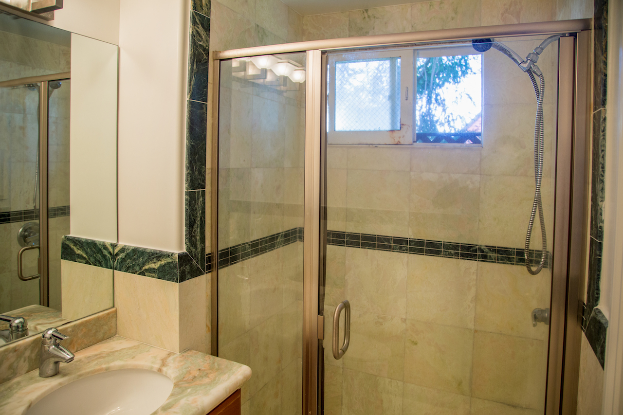 Modern bathroom with glass shower enclosure and marble countertop.