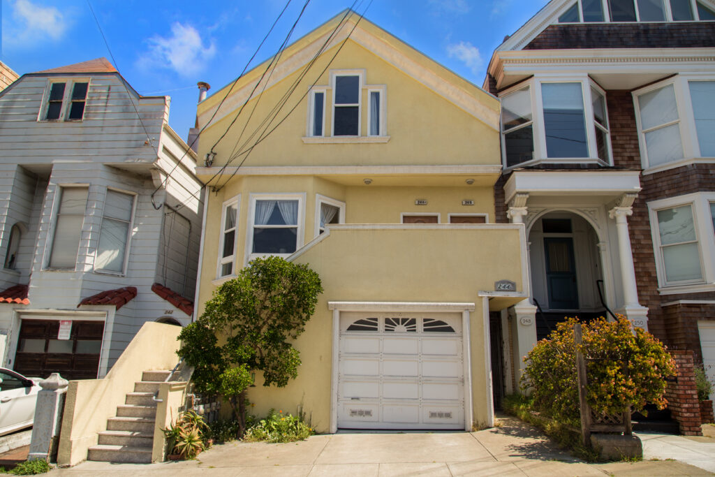 Yellow house with garage and staircase entrance.