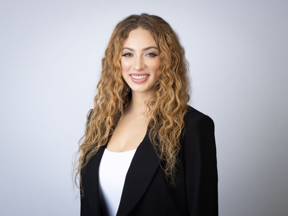 Professional woman with curly hair wearing a black blazer and white top.