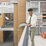 Man on balcony looking at smartphone.